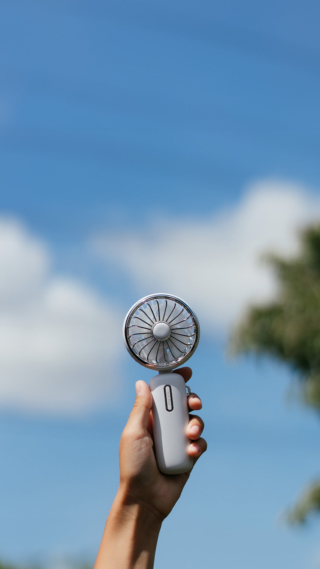 Individual showcasing a portable rechargeable handheld fan