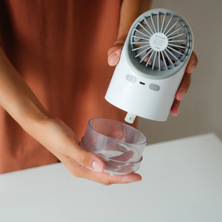 Individual holding a compact white mini fan humidifier