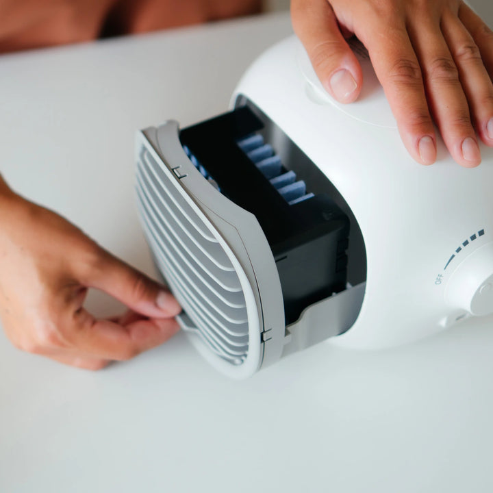 Individual setting up a small fan on a white table